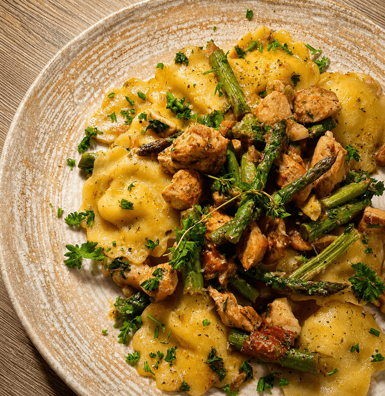 Close-up of a rustic ceramic plate with girosalli pasta filled with ricotta and asparagus, topped with sautéed chicken, asparagus pieces, herbs, and a sprinkle of black pepper.